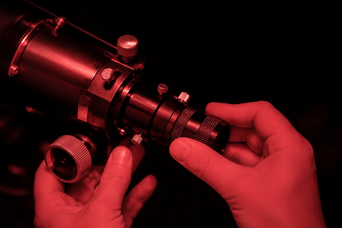 Réglage d’un oculaire sur un télescope installé dans un jardin sombre, ciel étoilé au-dessus
