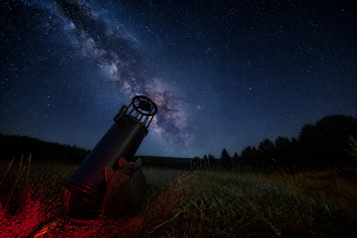 Télescope Dobson de 250 mm installé dans un pré, tube ouvert pointé vers la Voie lactée